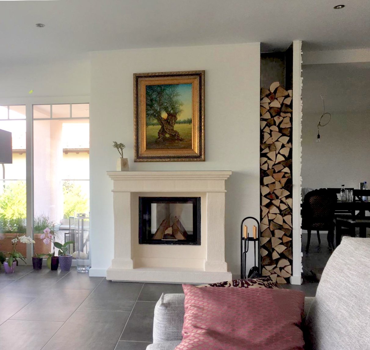 Klassischer Kamin mit Natursteinverkleidung in modernem Wohnzimmer mit Holzlager